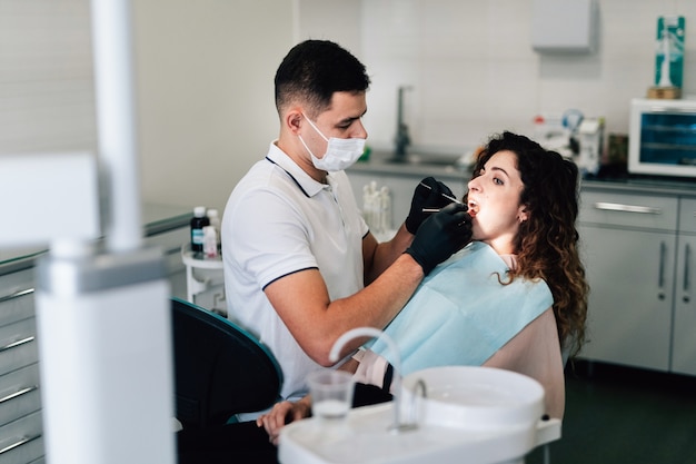 Dentist using equipment for teeth polishing for her teenage patient